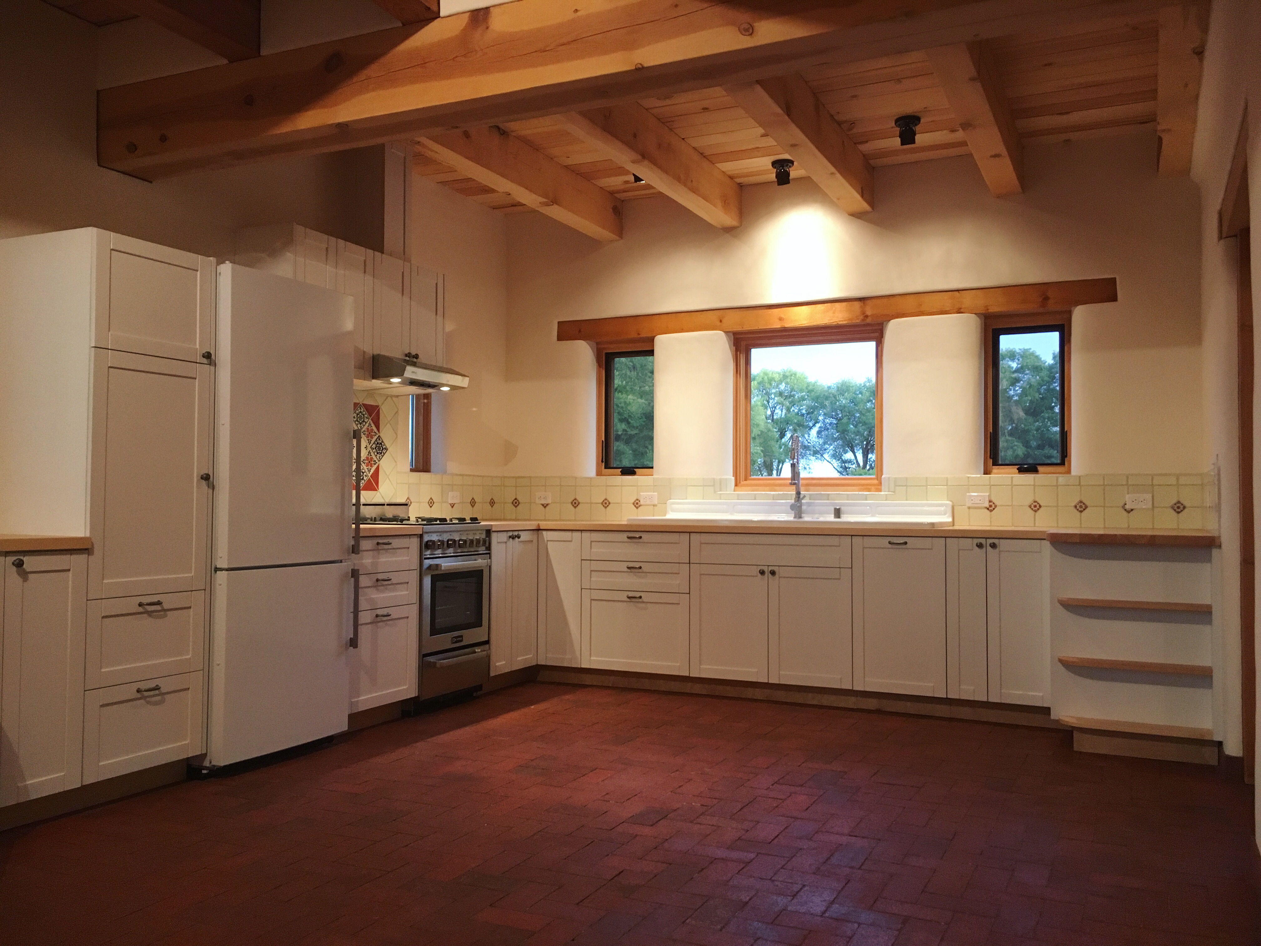 Adobe house interior, designed and built by Kenny DeLapp and Esther Fredrickson. Adobe house kitchen with brick floors and exposed vigas